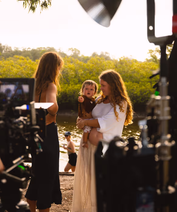 A film set by the river with a camera and a boom mic.
